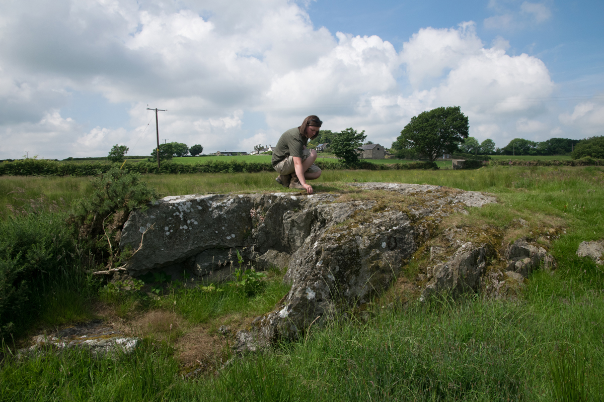 Dr Ffion Reynolds examining nearby outcrops for carved cupmarks. Anglesey, Wales