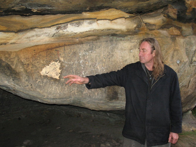 Archaeologist Wayne Brennan points to graffiti and vandalism at the Emu Cave rock art site in the Blue Mountains, NSW.