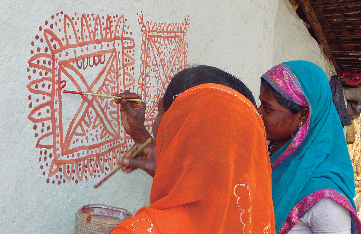 Korku women paint traditional designs on the wall of their home during wedding or Diwali festival